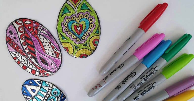 3 brightly decorated zentangle foil eggs on a white surface next to a set of bright colored sharpie marker