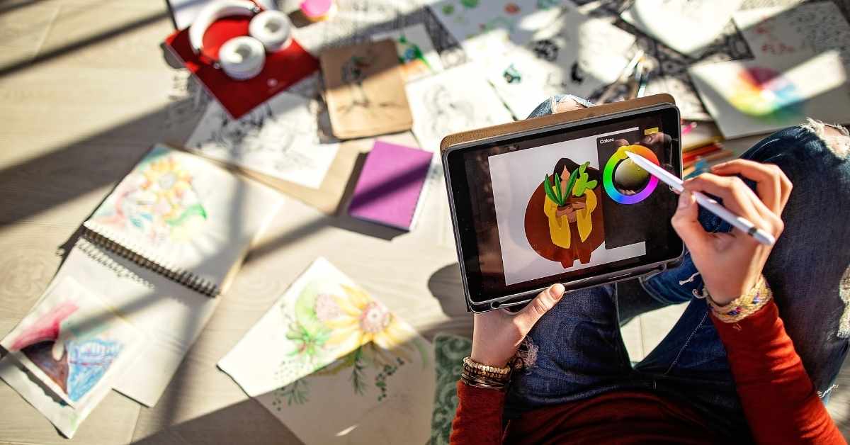 a hand doing a multicolored digital painting on a tablet
