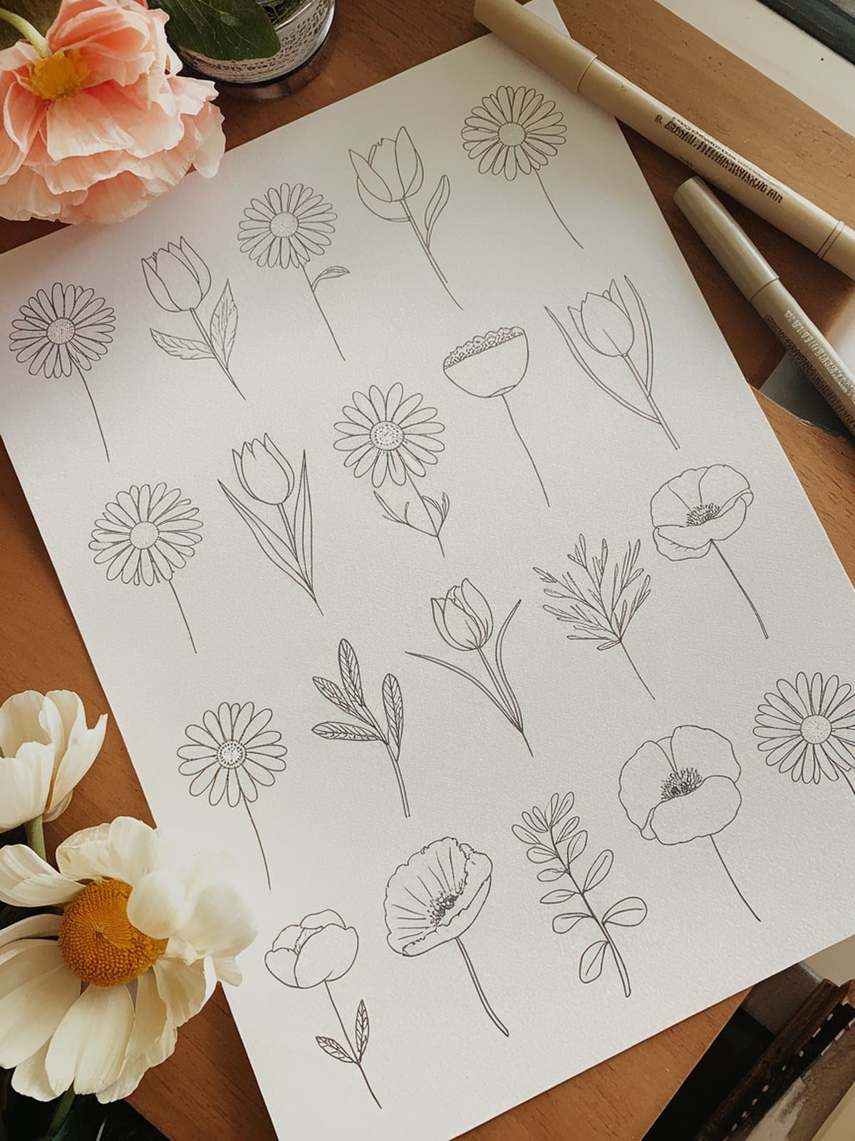 Grid of simple flower sketches showing daisies, tulips, and wildflowers in a clean line art style on white paper