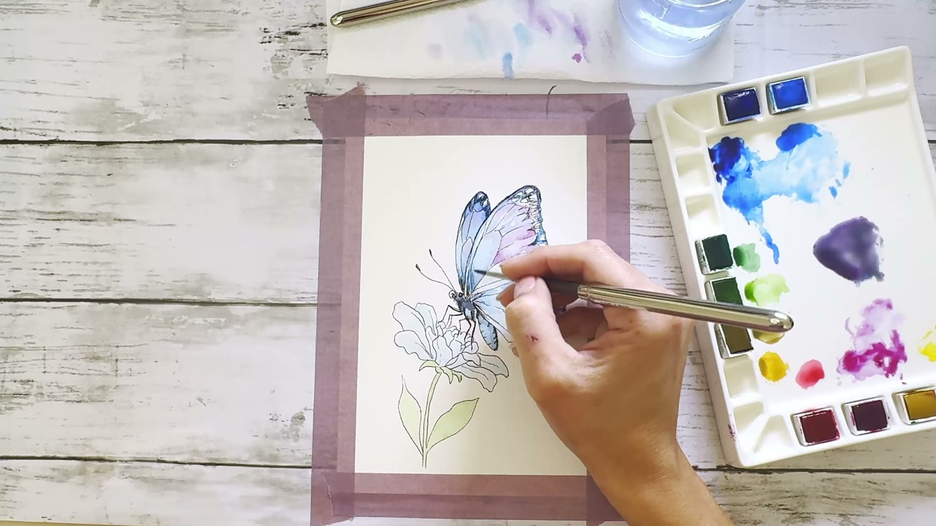 Dee's hands painting a watercolour butterfly, still from an Artsydee YouTube tutorial
