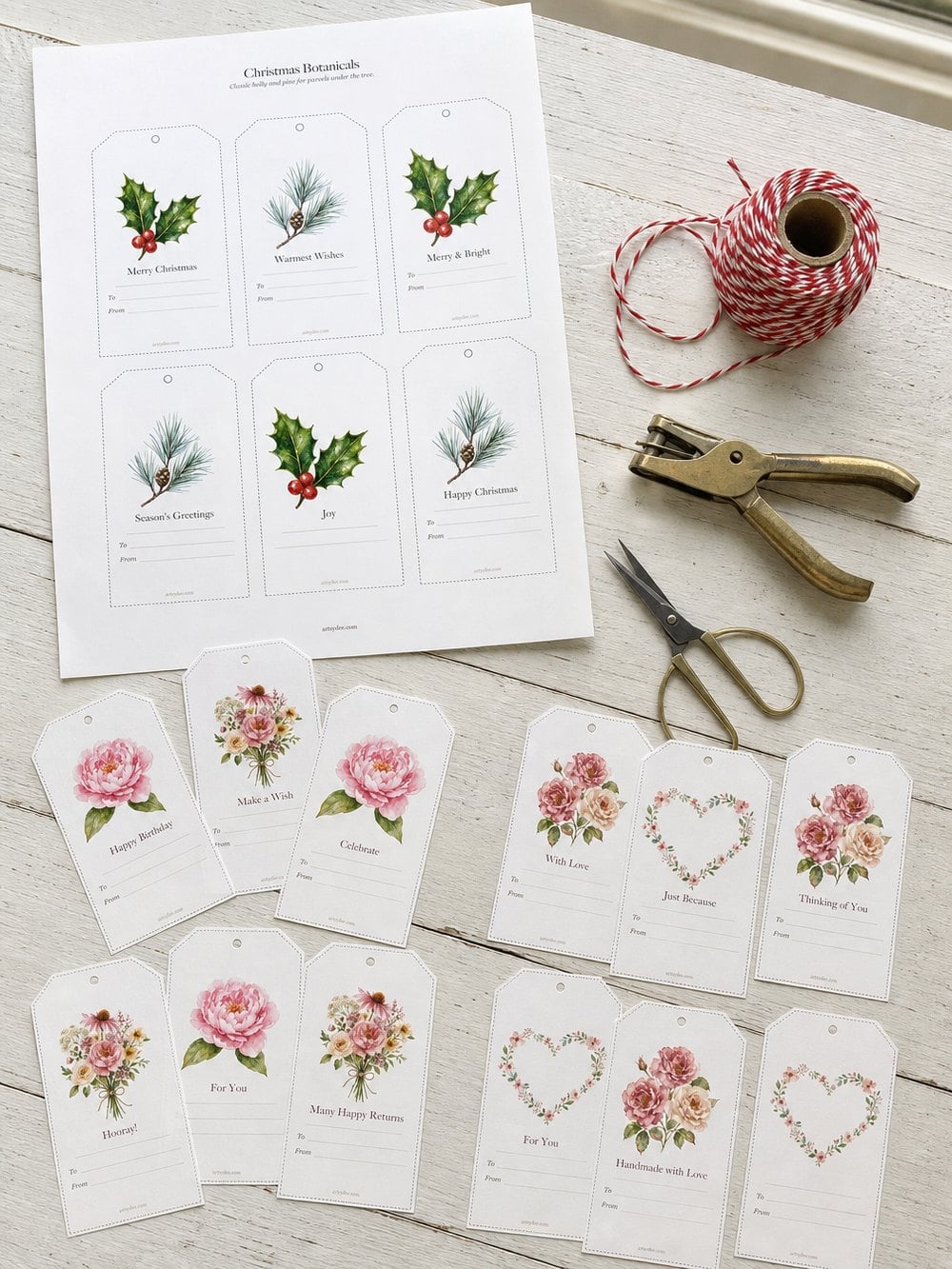 A printed sheet of gift tags part-way through being cut out, with twine and a hole punch
