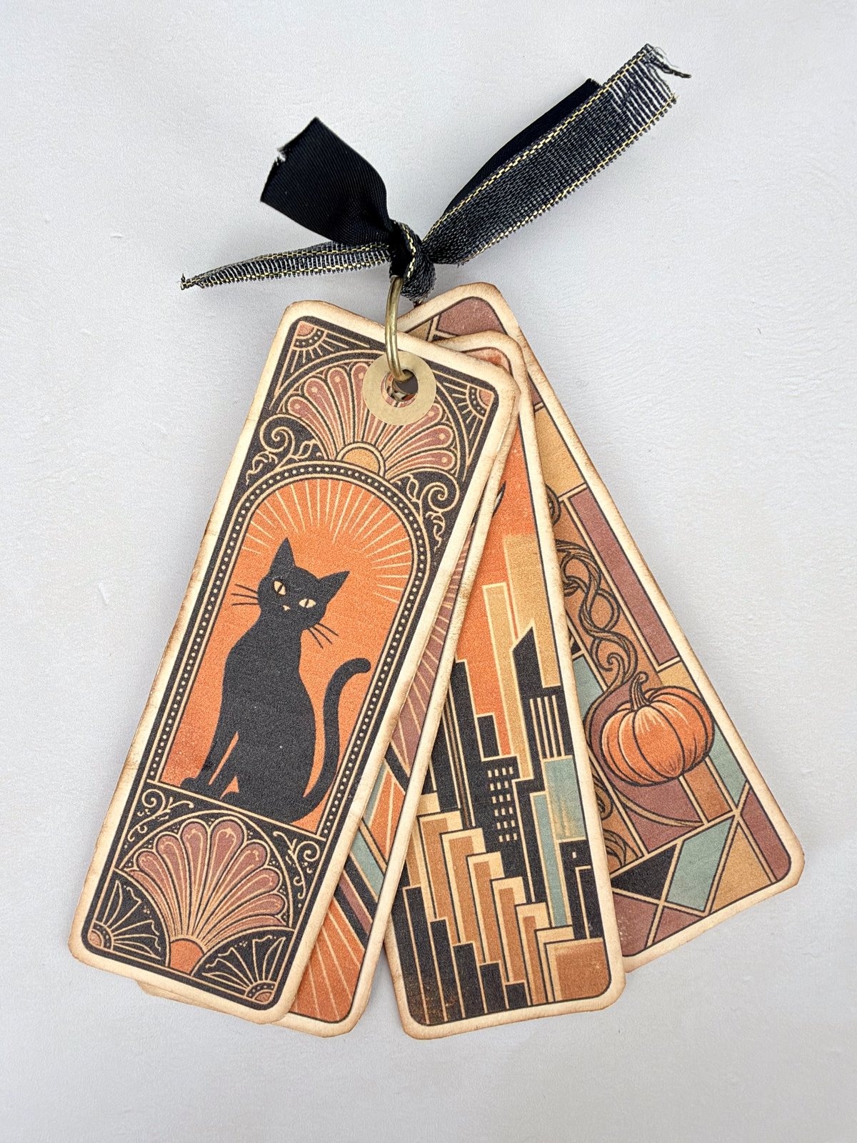 Four art deco style junk journal bookmarks gathered on a metal ring and tied with black ribbon