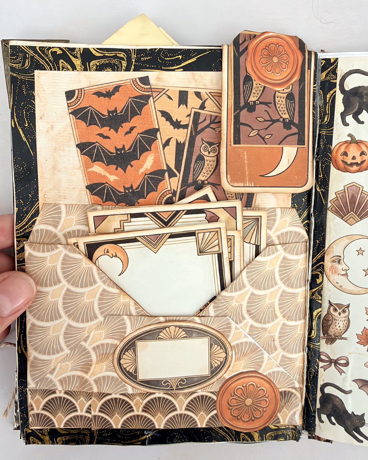 A patterned paper pocket on a junk journal page stuffed with journaling cards and tags