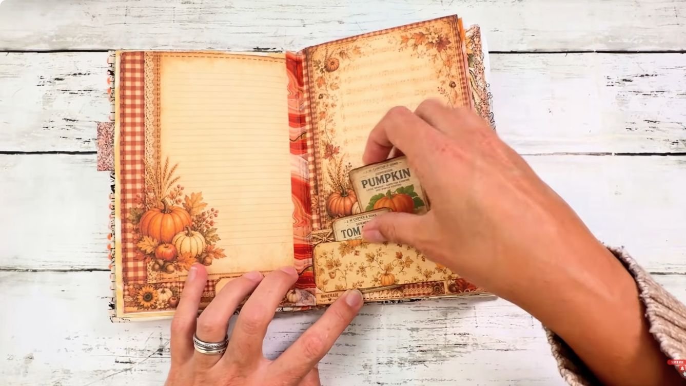 Hand sliding vintage vegetable labels out of a mini belly band in a junk journal