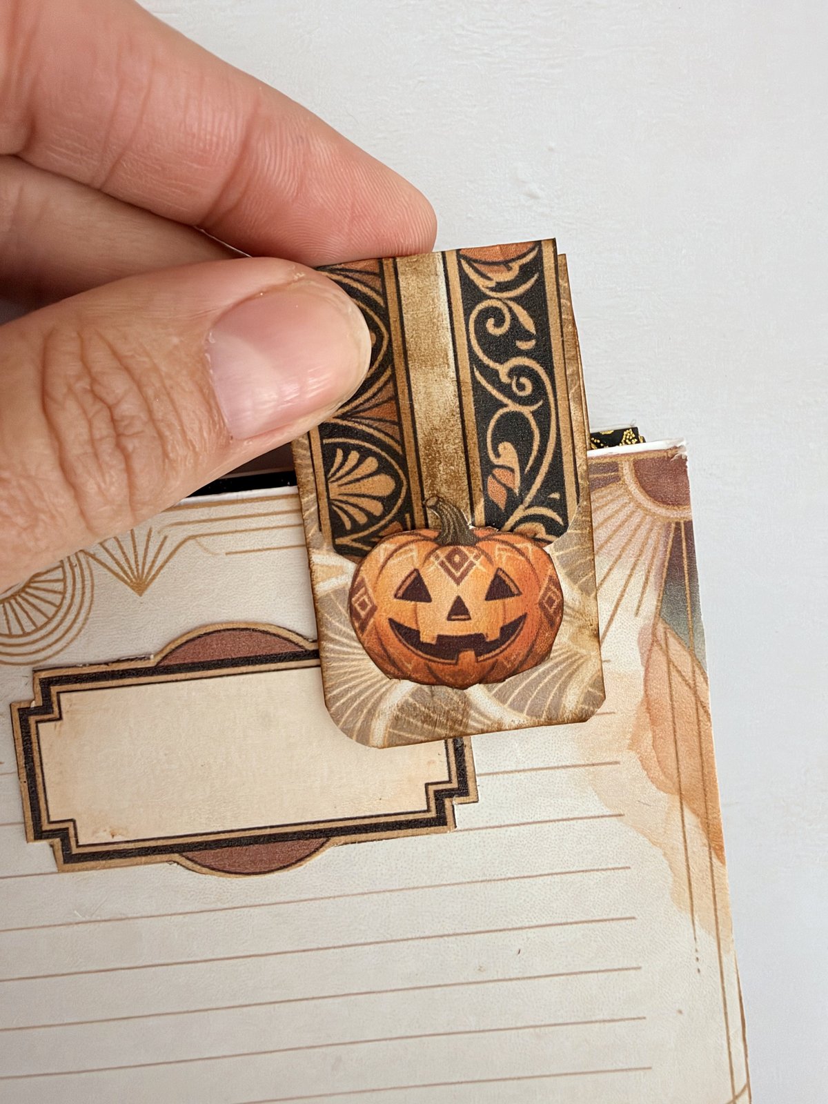 A pumpkin paper-clip topper clipped to the edge of a junk journal page