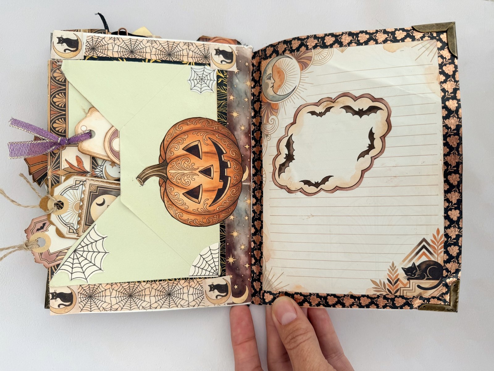 Junk journal spread with a patterned paper border, corner pieces and an envelope with a pumpkin