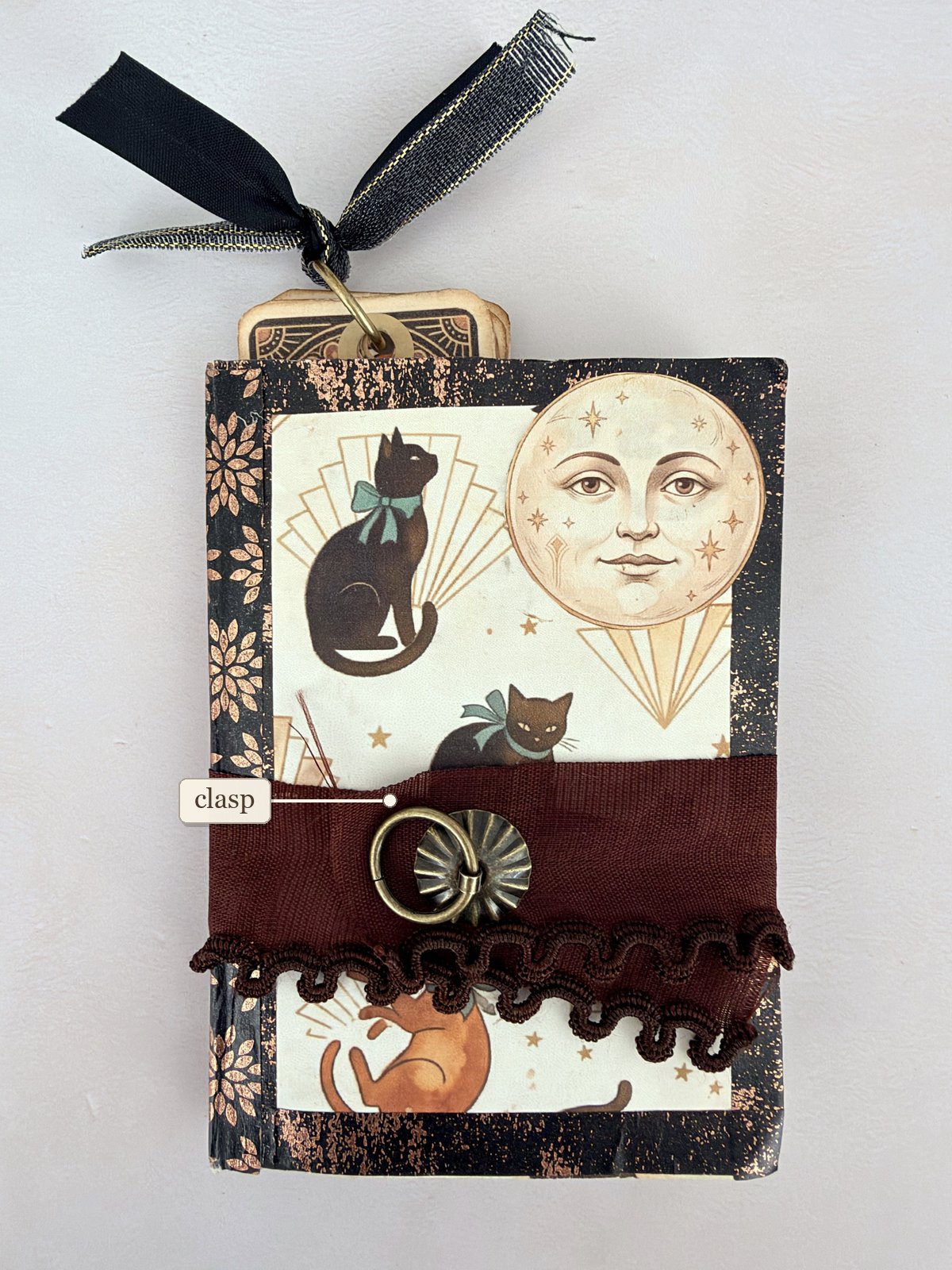 Small handmade junk journal with a brown ribbon band and a metal ring clasp