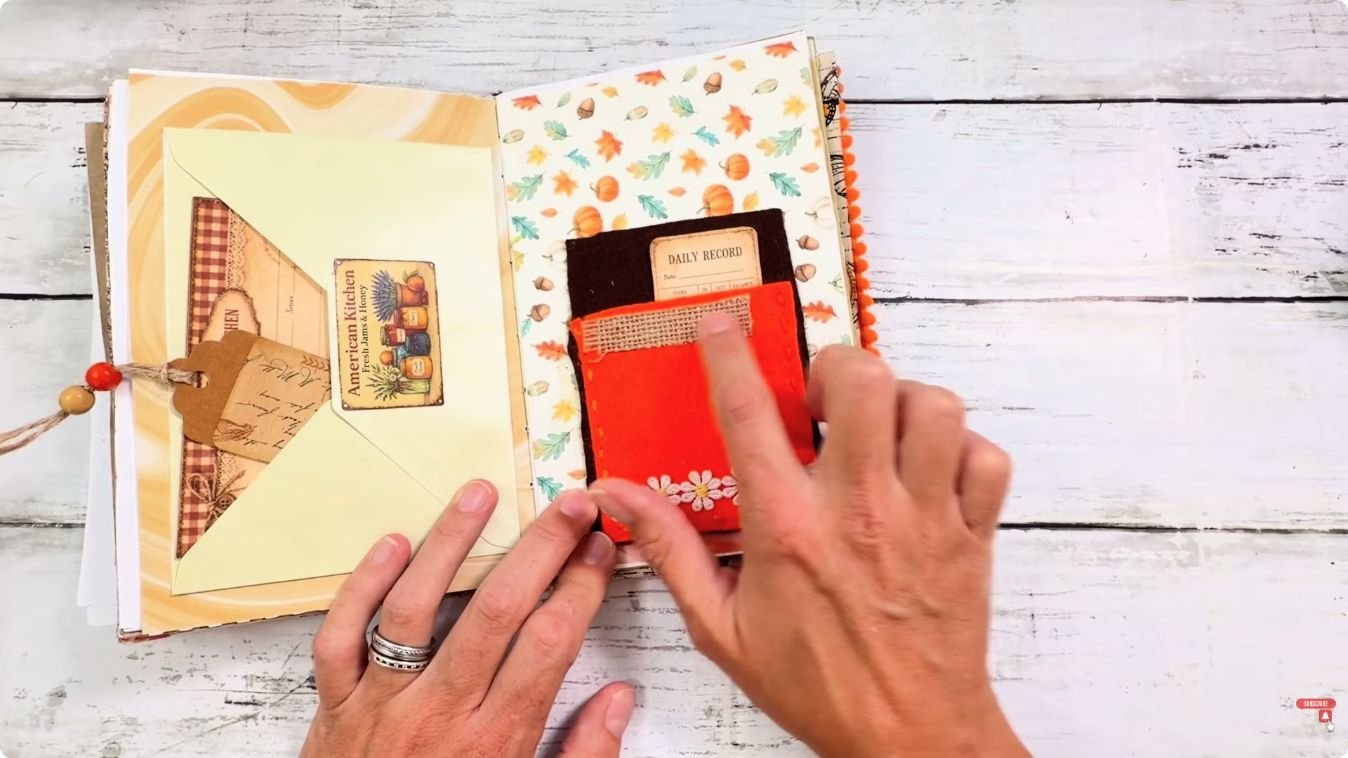 Hands showing a stitched felt pocket with daisy trim next to a pale green envelope