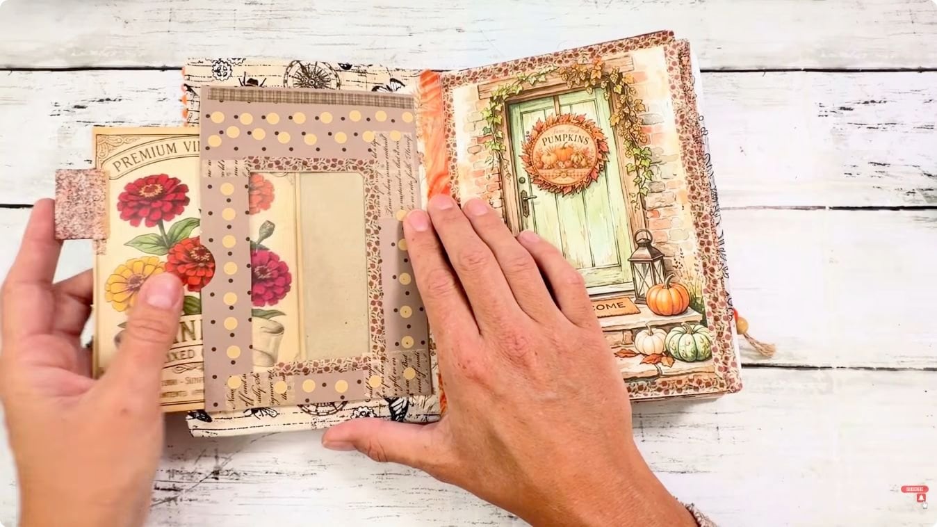 Hands sliding a vintage seed packet card out of a window pocket in a junk journal