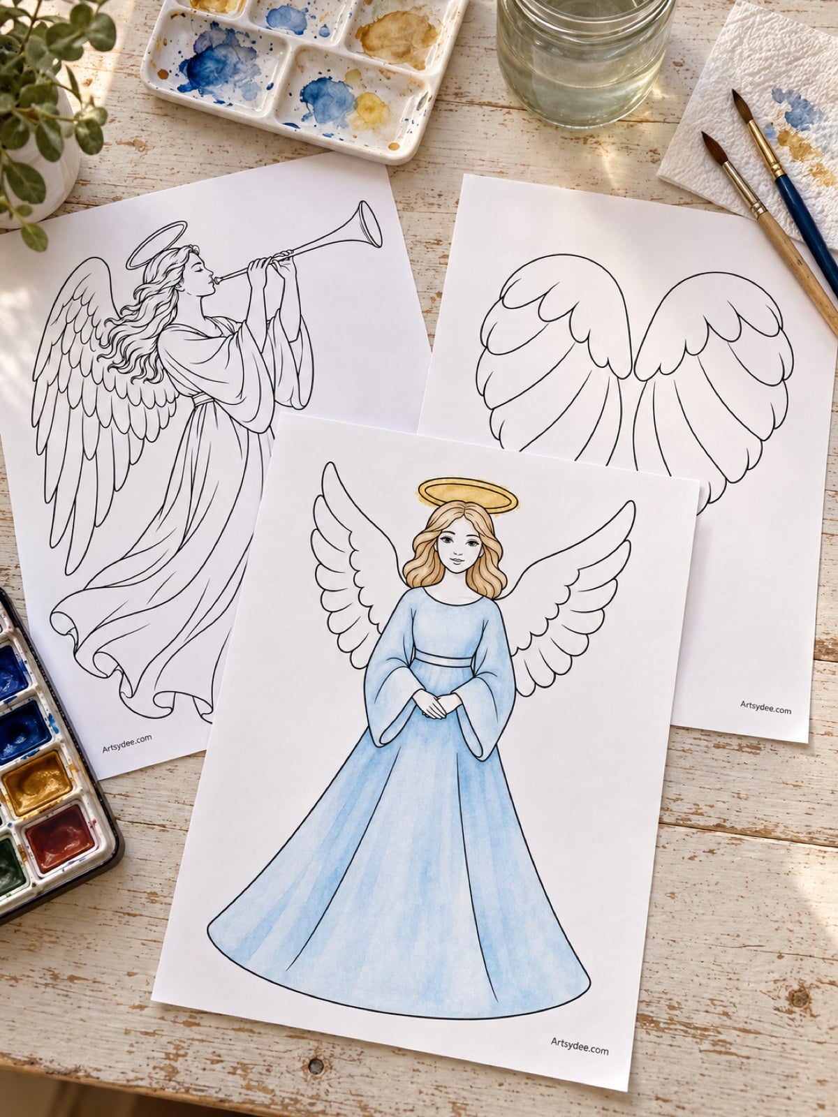 Illustrated mockup of printed angel templates on a desk, with one angel coloured in soft blue pencil
