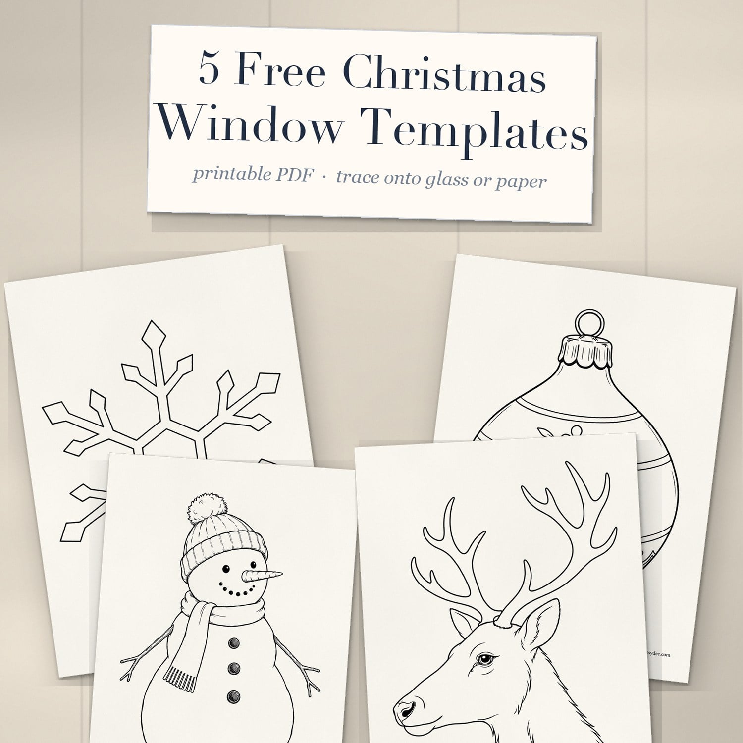 Printed Christmas window drawing templates of a snowflake, bauble, snowman and reindeer head on a desk under a cream title card reading 5 Free Christmas Window Templates