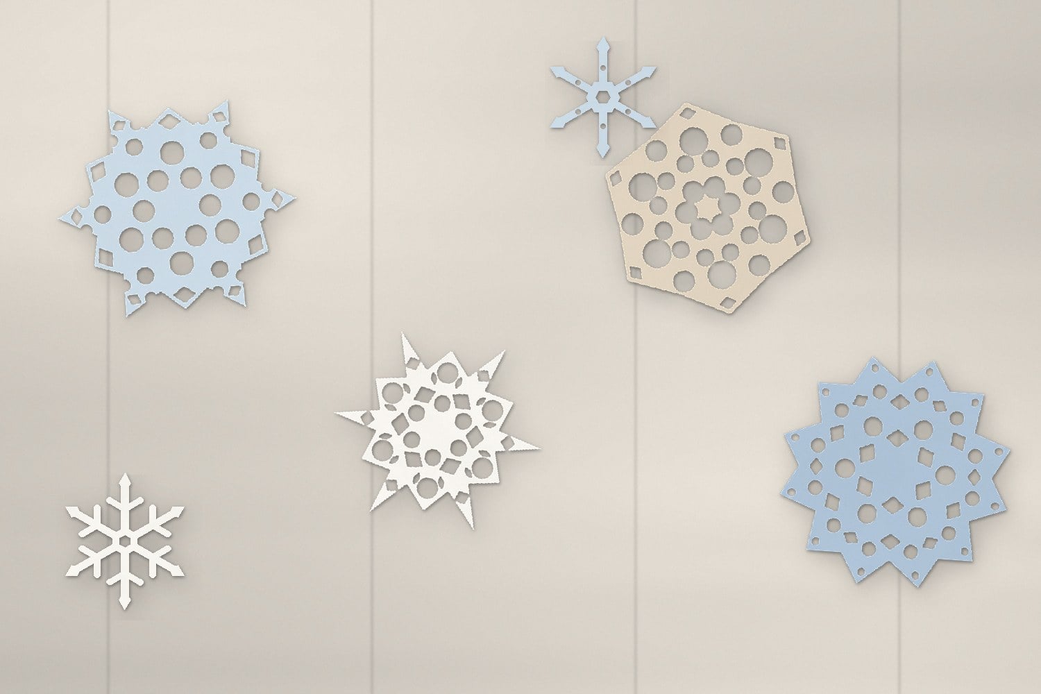 Blue, white and kraft paper snowflakes cut from the free templates, scattered on a white-washed desk