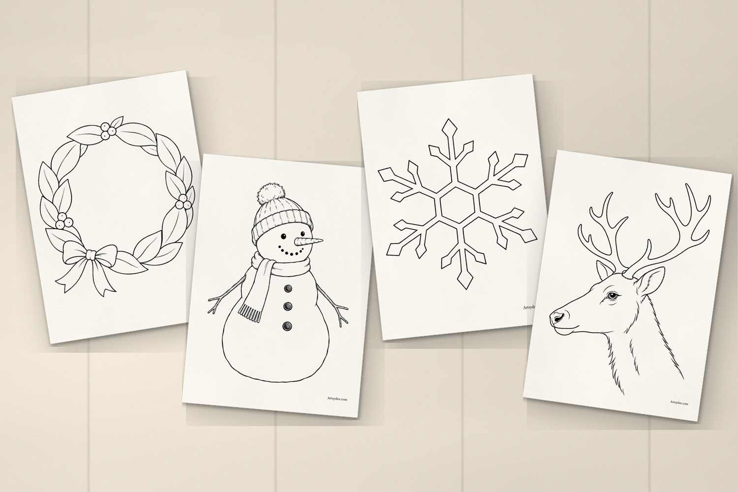 Four printed Christmas window templates on a desk: the wreath, the snowman, the snowflake and the reindeer head