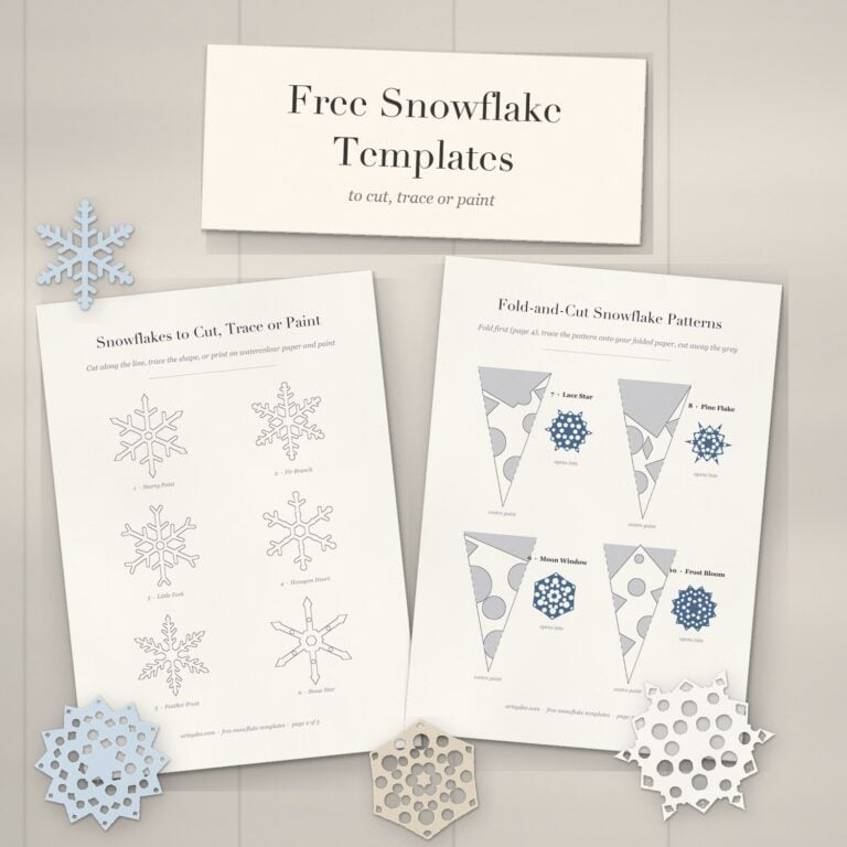 Printed free snowflake templates on a white-washed desk with paper snowflakes cut from the fold-and-cut patterns