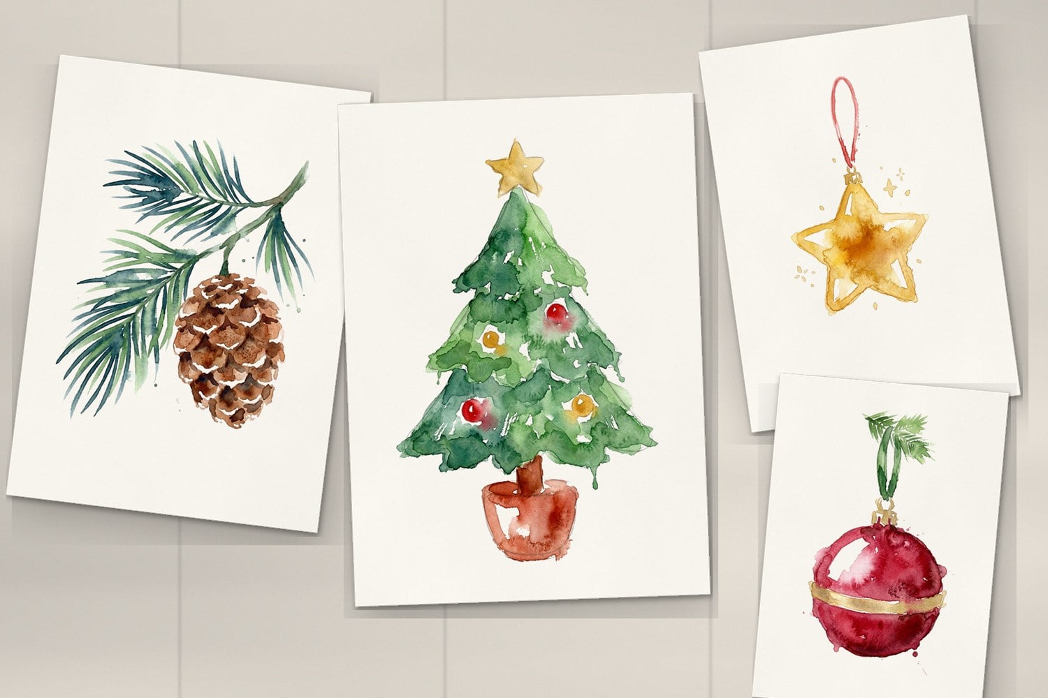Painted references of a watercolor Christmas tree, a pine sprig with a cone, a gold star and a red bauble on a desk
